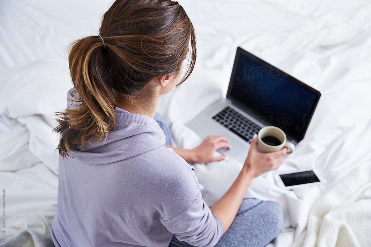 Woman holding a cup of coffee in front of a laptop