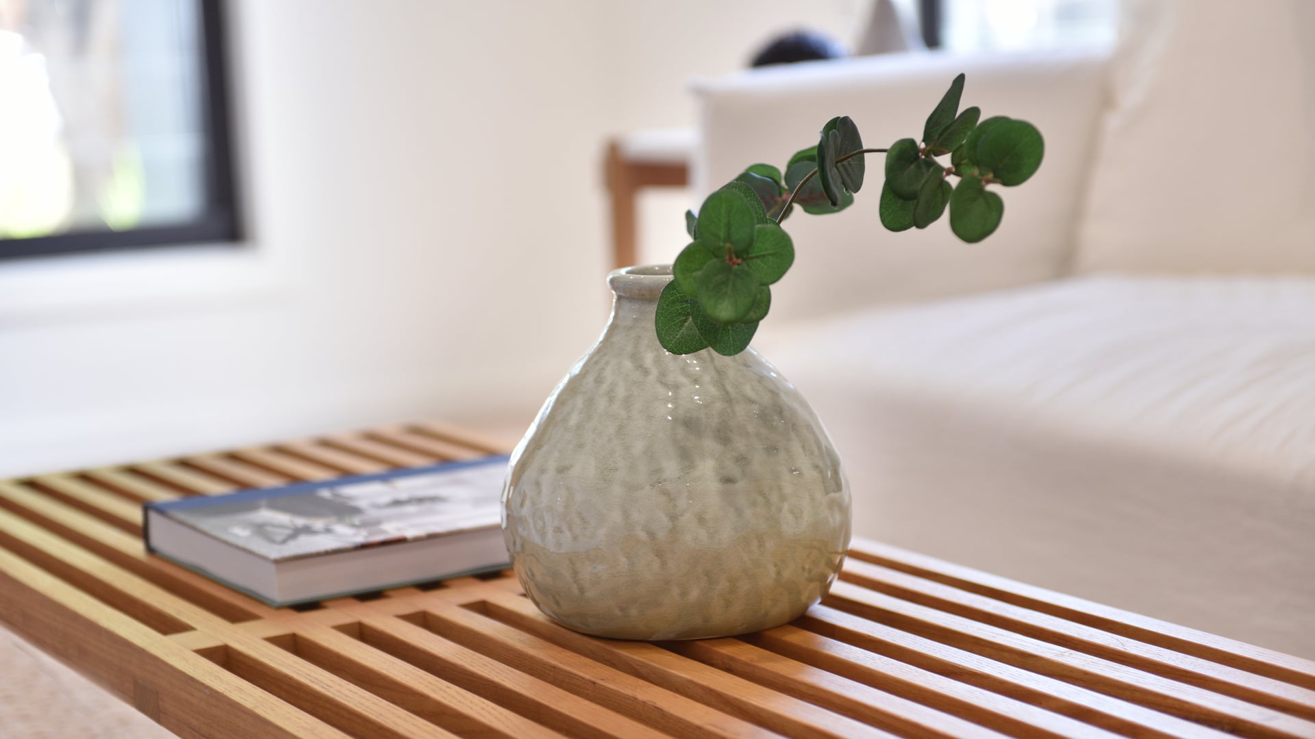 White flower vase beside a book